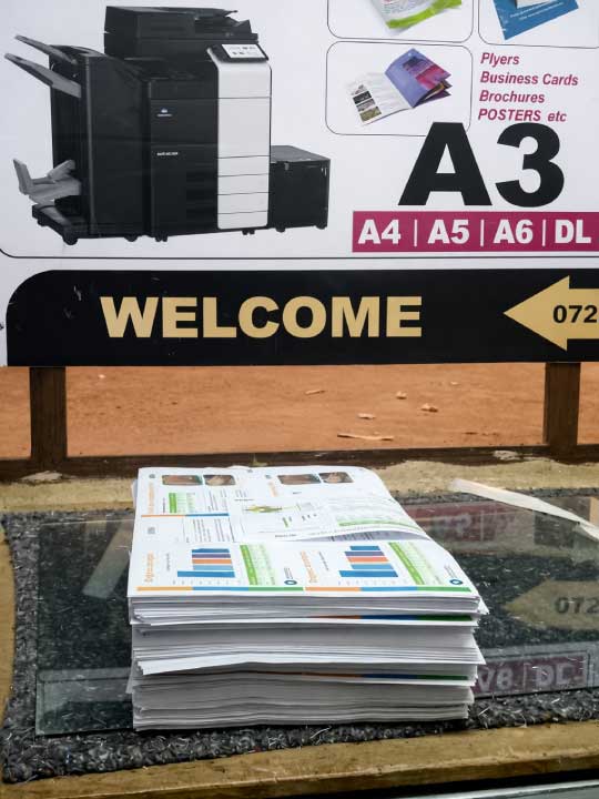 Stack of professionally printed A3 documents displayed in front of a digital press printing sign, representing high quality digital printing services in Nairobi, Kenya.
