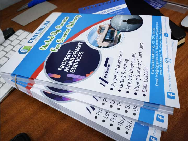 Stack of professionally printed full colour flyers on an office desk, showcasing high quality digital printing services in Nairobi, Kenya.