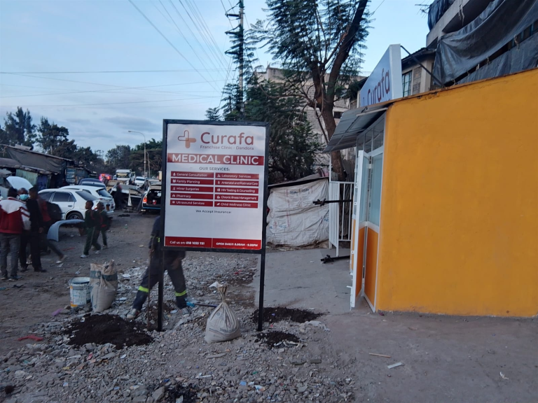 Freestanding Curafa Medical Clinic sign beside its Dandora premises in Nairobi, Kenya.
